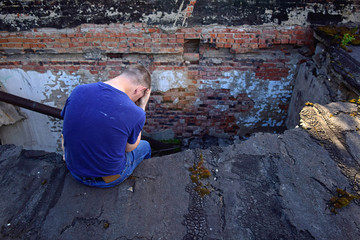 On the roof of the emergency house sits a man. The man is desperate, his house is destroyed.