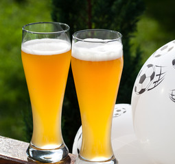 two glasses of beer and balloon with footballs - watching soccer