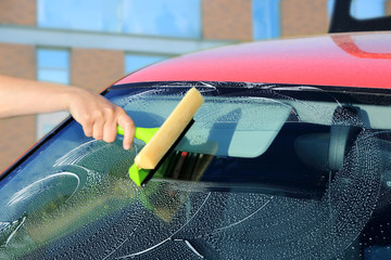 Auto serwis, kierowca myje przednią szybę w samochodzie osobowym,