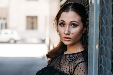 Emotional portrait of Fashion stylish portrait of pretty young woman. city portrait. sad girl. brunette in a black dress. expectation. dreams