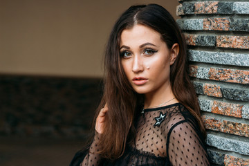 Emotional portrait of Fashion stylish portrait of pretty young woman. city portrait. sad girl. brunette in a black dress. expectation. dreams. stands near the wall