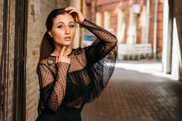 Fototapeta premium Emotional portrait of Fashion stylish portrait of pretty young woman. city portrait. sad girl. brunette in a black dress. expectation. dreams