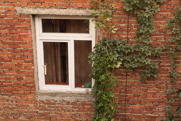 Fototapeta na wymiar An old brick wall with a white window.