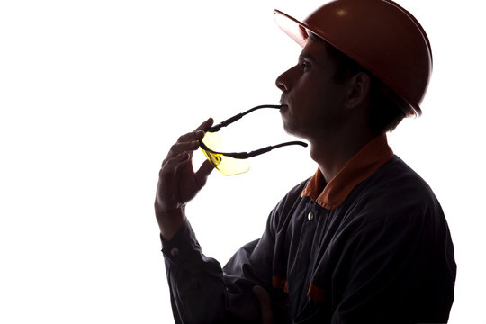 silhouette of a young constructer thinking of a career, a man in a helmet on a white isolated background