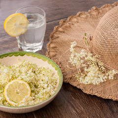 Freshly picked elderberry flowers in a beautiful ceramic bowl with lemon slices as decoration. The...