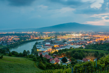 The magnificent view of the city of Maribor, Slovenia, Central Europe from Meljski hrib. Pohorje hills in the background, river Drava and street lights shining brightly on a stormy spring night.