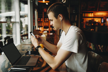 Male using smartphone sitting in cafe