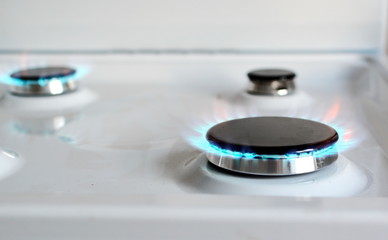 Three burning white gas stove hob blue flames. Front view