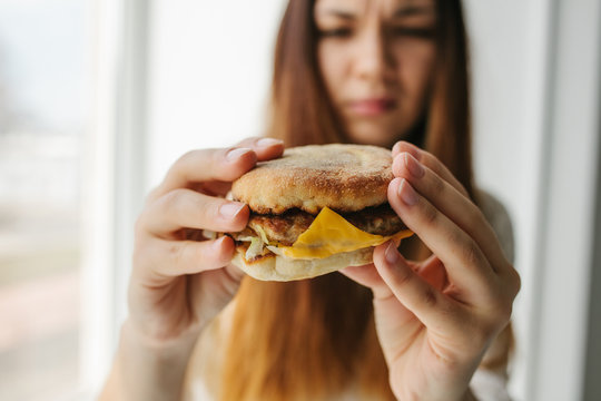 A young girl shows that she does not like a burger. Conceptual image of refusal from unhealthy eating.