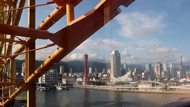 view of the city of Kobe from the window of a rotating cabin on a Ferris wheel.