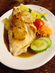 delicious traditional western styled food, chicken steak stuffed with cheese garnished with parsley, pepper and sided by seasonal vegetable, potato cucumber tomato carrot.