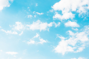 Blue sky with torn white formless clouds.