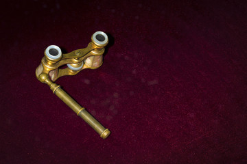Opera glasses on burgundy background with space for text