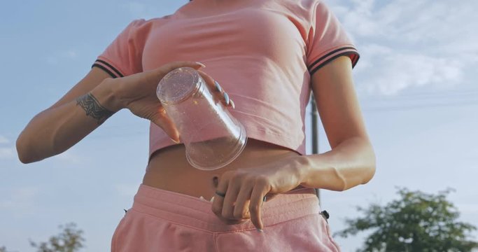 Funny girl pours popcorn from a glass in pink shorts. 4K video shooting by handheld gimbal