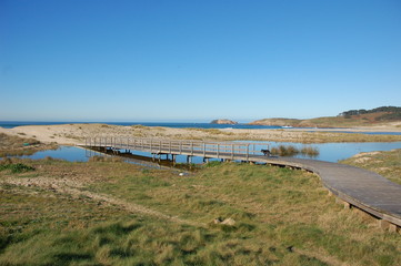 Fototapeta na wymiar Beach of Doniños in north west of Spain. A wooden bridge cross the river created by the winter's rains.