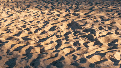 Sand texture with shadows in sunset light. Sandy beach as background