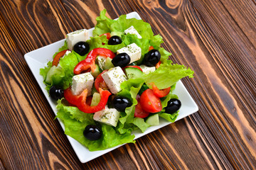 Greek salad on a wooden background. Space for text or design.
