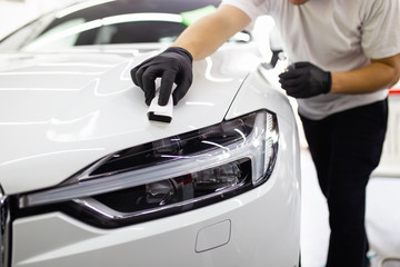 Car detailing - Worker polishing car in auto repair shop. Selective focus.