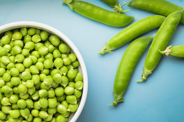 Concept of healthy eating. Fresh green peas in pods and peas. Blue background