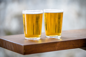 Two glasses of beer are on the bar