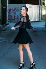 Emotional portrait of Fashion stylish portrait of pretty young woman. city portrait. beautiful brunette whirls around in the city. happy and cheerful. black dress.