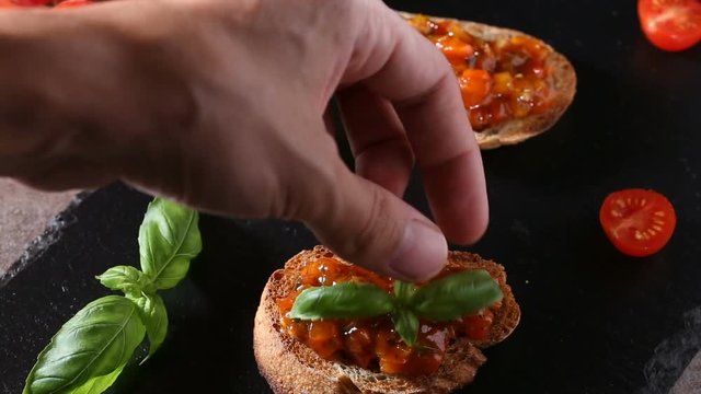 Serving Homemade Italian antipasto called Bruschetta topped with tomatoes, garlic, red pepper and basil 