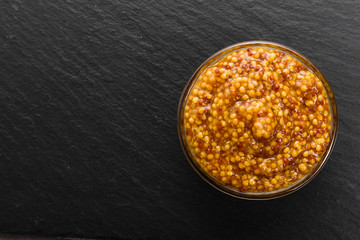 mustard in a bowl on a rustic background