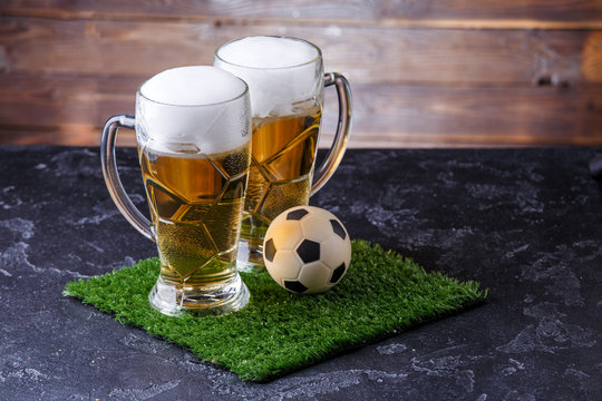 Picture of two glasses of beer, soccer ball on green grass
