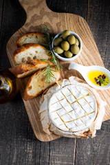 Baked camembert cheese. Fresh Brie cheese and a slice on a wooden board with nuts, honey, rosemary,...