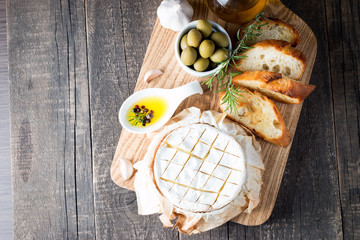 Baked camembert cheese. Fresh Brie cheese and a slice on a wooden board with nuts, honey, rosemary,...