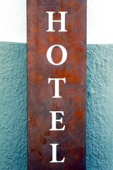 Schriftzug "Hotel" ; Metallschild, an einer Wand in graublau und weiß