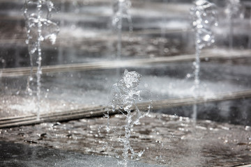 Splashing water from a fountain in the park as a background