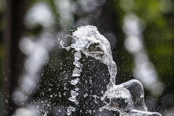 Splashing water from a fountain in the park as a background