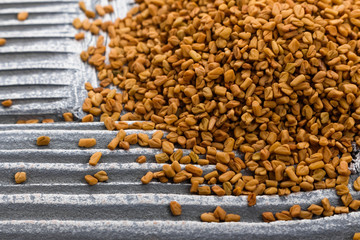 fragrant grains of fenugreek on a rustic background