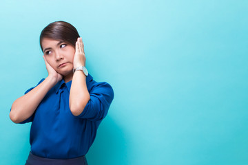 Asian woman covers ears with hands on isolated background