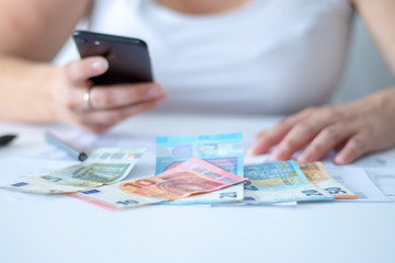 Diverse Euro Banknoten vor eine arbeitenden Frau in ihrem Büro am Schreibtisch