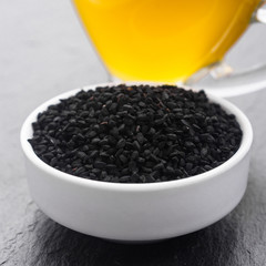 grains of black cumin and oil on the rustic background