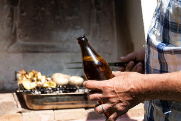 bottle of beer in man's hands while making barbecue