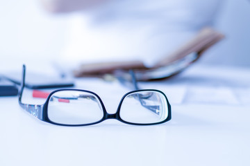 Brille auf dem Schreibtisch an einem Arbeitsplatz in einem Großraumbüro