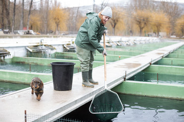Female catching fish from reservoir on sturgeon farm