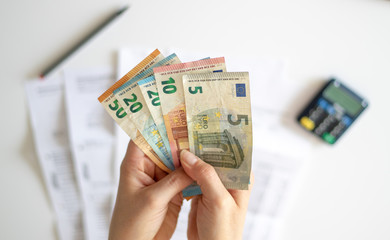Frau in einer Bankfiliale hält verschiedene Euro Geldscheine in ihren Händen über einem...
