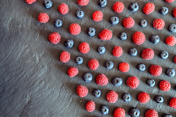 raspberries and blueberries arranged in a pattern of lines with copy space