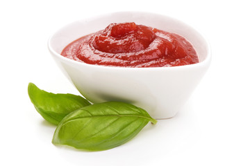 Bowl of ketchup or tomato sauce with herbs, isolated on white background.
