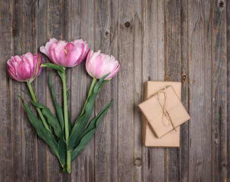 Pink terry tulips and craft gift box on rustic wooden background, Valentines Day or Mothers day background, top view.