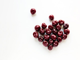 Cherries Top view Ripe cherries are lying in the shape of broken heart on a white background Photo with copy space