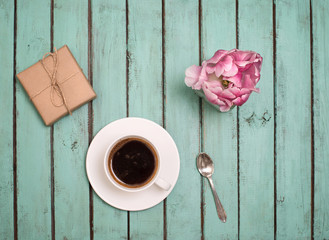 Pink terry tulip, cup of coffee and craft gift box on rustic wooden background, Valentines Day or Mothers day background, top view.