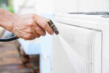 Repairman fixing and cleaning air conditioner unit by high pressure water jet