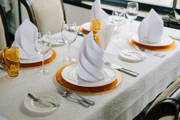 Wedding. Banquet. The chairs and round table for guests, served with cutlery, flowers and crockery and covered with a tablecloth