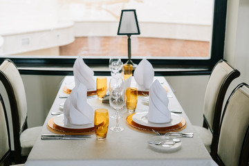 Wedding. Banquet. The chairs and round table for guests, served with cutlery, flowers and crockery and covered with a tablecloth