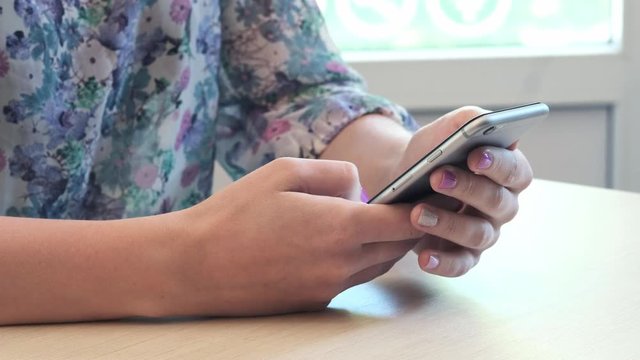 Closeup shot of female hands holding smartphone, typing text on touch screen. Woman answering friend message in social network application, searching for information. Worker spending break time online